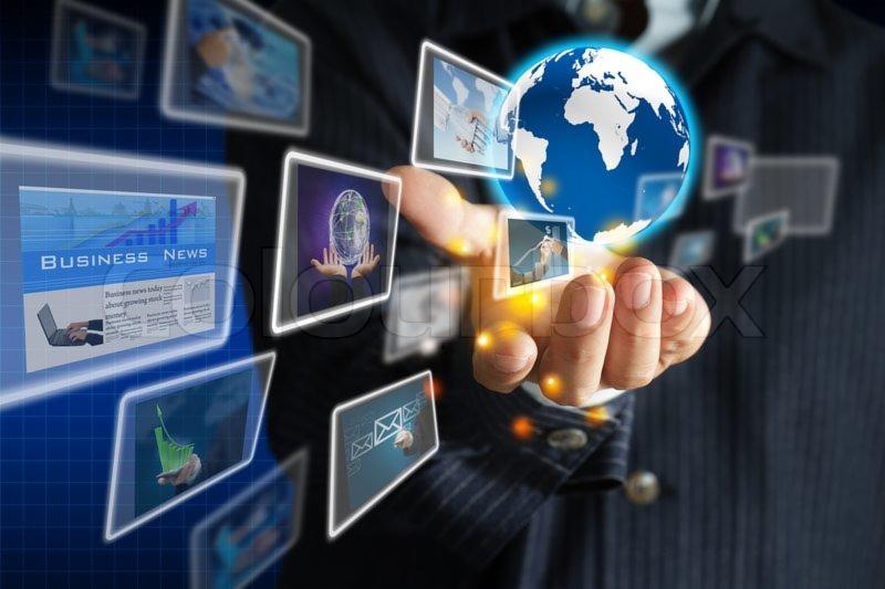 Mężczyzna w garniturze dotyka palcem wirtualnego globu otoczonego przez ekrany z treściami biznesowymi i grafami wzrostu.