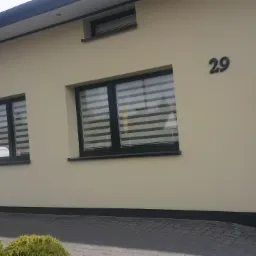 Elewacja budynku z numerem 29 w Kurzeszynie, po świeżym odmalowaniu na beżowo, z czarnymi ramami okiennymi i rynnami.