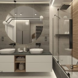 Studio Dobre Miejsce Sylwia Malewicz - Nowoczesna łazienka z okrągłym lustrem, dwiema białymi umywalkami nablatowymi, szarą armaturą i drewnopodobnymi płytkami w kabinie prysznicowej.