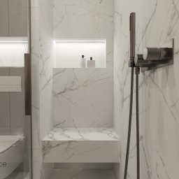 Studio Dobre Miejsce Sylwia Malewicz - Elegancka łazienka z marmurowymi płytkami, wnęką z oświetleniem LED i minimalistyczną armaturą w kolorze grafitowym. Widoczny fragment toalety za szklaną ścianką.