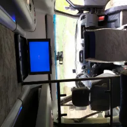 Wnętrze busa pasażerskiego z zamontowanym telewizorem i regulowanymi fotelami.