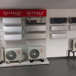 Ekspozycja różnorodnych modeli klimatyzatorów, w tym jednostki wewnętrzne i zewnętrzne, marki Rotenso i Ande prezentowane w sklepie, niektóre jeszcze w folii ochronnej.