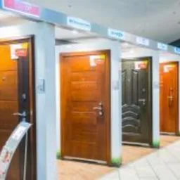 Ekspozycja różnorodnych drzwi zewnętrznych w salonie, widok z perspektywy klienta, prezentujące różne wzory, kolory i materiały wykończeniowe.