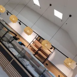 Wnętrze lokalu handlowego we Wschowie z zamontowanymi lampami wiszącymi z abażurami z plecionej wikliny, widok na oświetlenie i meble ekspozycyjne przed otwarciem.