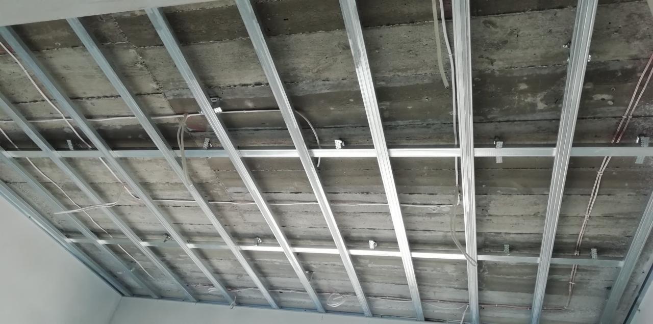 Stelaż sufitu podwieszanego z widocznymi przewodami elektrycznymi przed montażem płyt gipsowo-kartonowych.