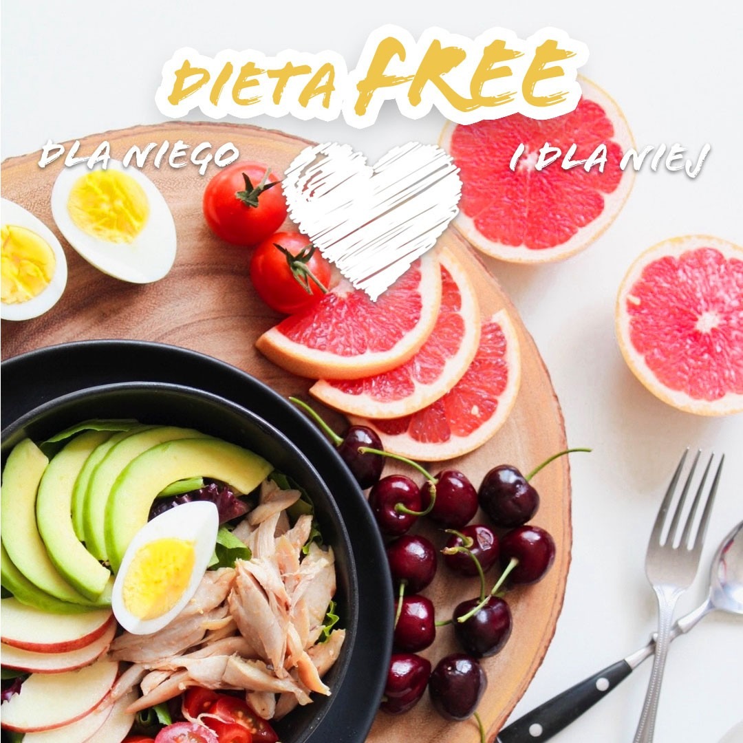 Kompozycja z czarnej miski z sałatką z awokado, kurczaka i jajka, otoczonej połówkami grejpfruta, wiśniami, pomidorkami koktajlowymi i jajkami na twardo, ułożona na drewnianej desce obok sztućców.