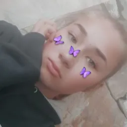 Portret młodej osoby z filtrem motyli na twarzy, leżącej na kamiennej powierzchni.