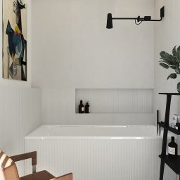 Moduu Magdalena Rosowska - Minimalistyczna łazienka z białą wanną, czarną lampą i półką na kosmetyki. Obraz w stylu Picassa dodaje charakteru. Krzesło i roślina ożywiają wnętrze.