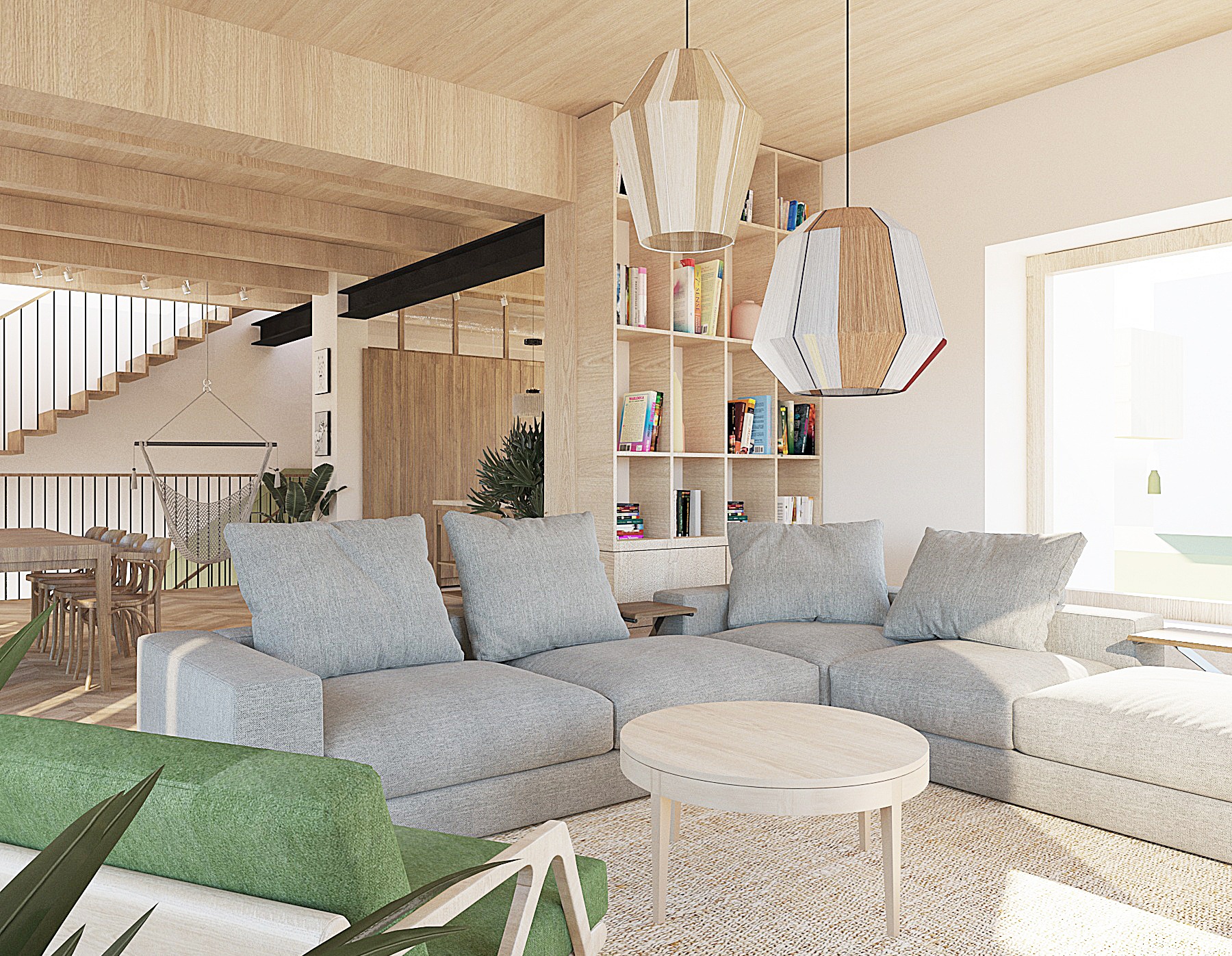 Jasne, przestronne wnętrze domu z drewnianymi elementami, szarą sofą modułową i okrągłym stolikiem kawowym. Widoczne schody i regał z książkami. Dwie lampy wiszące.