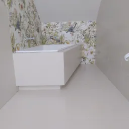 Nowoczesna łazienka na poddaszu z wanną obudowaną płytami w kolorze ecru i ścianami wykończonymi płytkami z motywem kwiatowym.