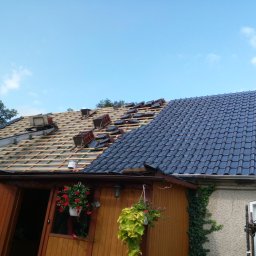 Jar-Bud - Częściowo pokryty dachówką dach w Żarach. Widoczne drewniane łaty i przygotowane dachówki. Część dachu już ukończona, ciemna dachówka. Prace dekarskie w toku.