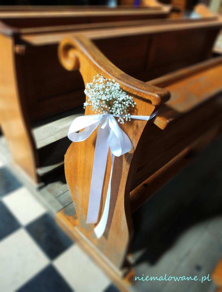 Dekoracja kościelnej ławki: bukiecik gipsówki z białą wstążką, oświetlony bocznym światłem, na tle czarno-białej podłogi.