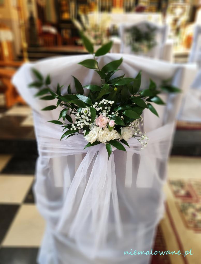 Udekorowane krzesło w kościele, biały tiul i kompozycja kwiatowa z gipsówki, różowych i białych róż oraz zielonych liści.