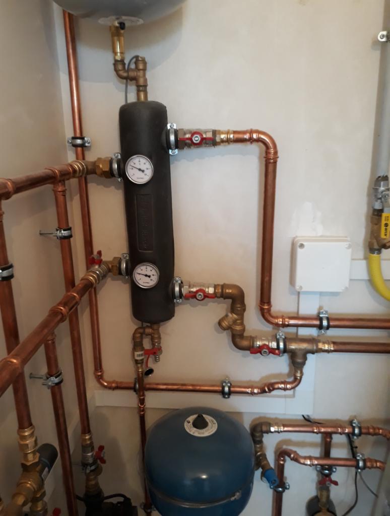 Instalacja hydrauliczna z miedzianymi rurami, manometrami i zaworami w kotłowni w Lublinie, widoczne elementy centralnego ogrzewania.