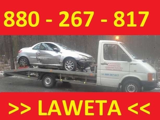 Laweta z uszkodzonym srebrnym samochodem osobowym na platformie, widoczne dane kontaktowe na pojeździe.