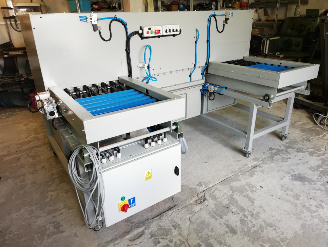 Profesjonalna, dwustronna maszyna do obróbki z niebieskimi rolkami, pneumatycznymi przewodami i panelem sterowania, ustawiona w warsztacie.