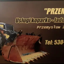 Wizytówka firmy 'Przemko' oferującej usługi koparko-ładowarką, z numerem telefonu 530-114-144, na ciemnym tle z ilustracją koparko-ładowarki.