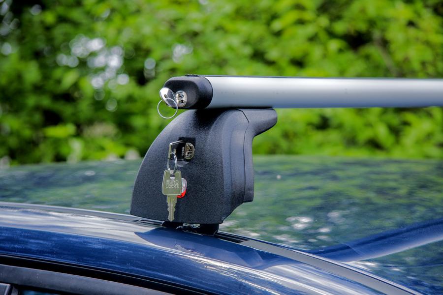 Bagażnik dachowy z zamkiem na samochodzie, kluczyk Euro Locks w zamku, tło z zielenią