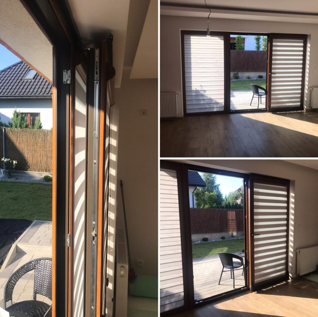 Widok z bliska na mechanizm przesuwny i zamknięte poziome pasy materiału w oknie tarasowym, z widokiem na ogród i dom w tle, ujęcie z wnętrza pomieszczenia.