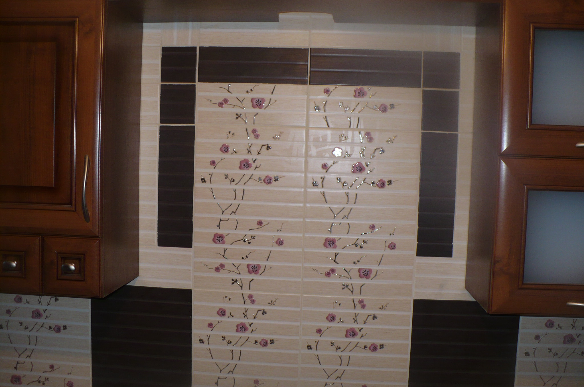 Beżowe płytki z motywem kwiatowym w łazience, otoczone brązowymi szafkami.