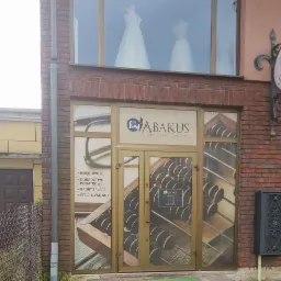 Fasada budynku z szyldem 'ABAKUS BIURO RACHUNKOWE', oklejona grafiką przedstawiającą liczydło i okulary, w oknach widoczne suknie ślubne