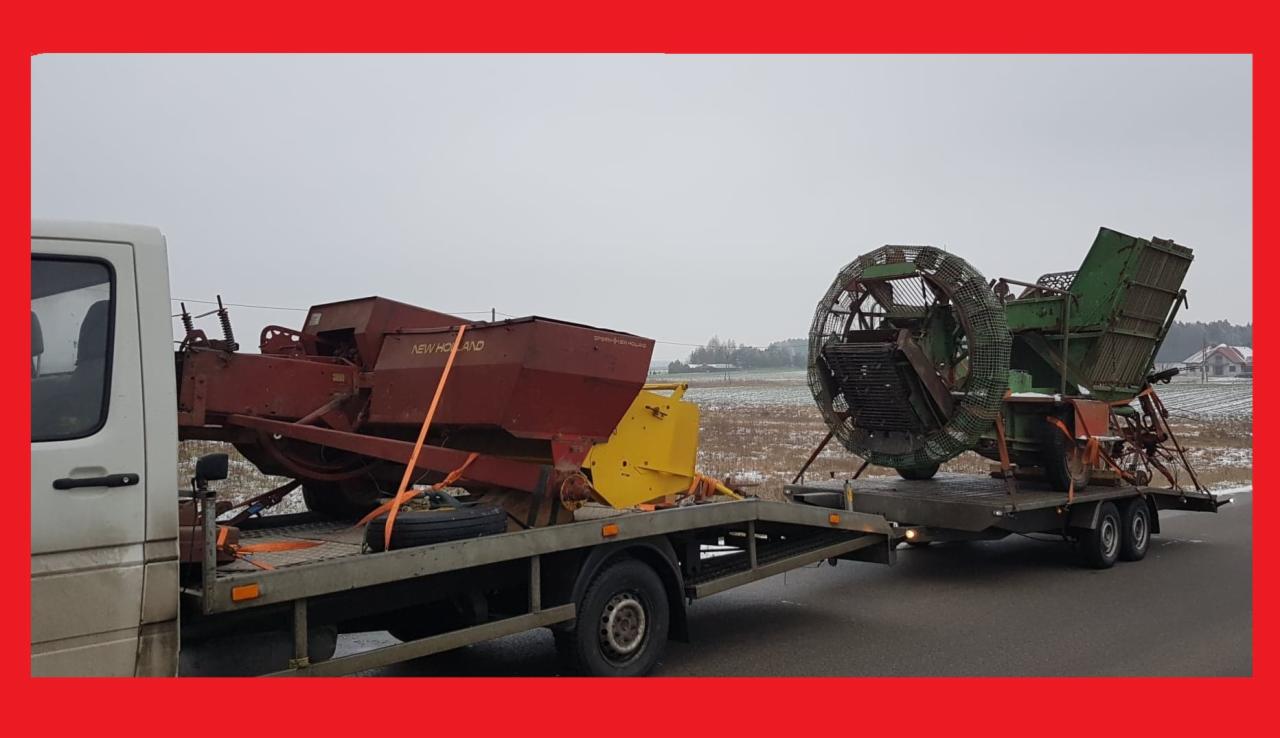 Laweta z białym busem przewozi dwa duże, używane maszyny rolnicze: siewnik New Holland w kolorze czerwonym i żółtym oraz zieloną maszynę do sortowania ziemniaków, zabezpieczone pomarańczowymi pasami.