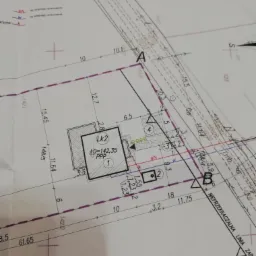 Skan projektu zagospodarowania działki z naniesionym obrysem budynku, wymiarami i oznaczeniami punktów geodezyjnych, widoczna nieprzekraczalna linia zabudowy.