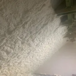 Poddasze po aplikacji izolacji z pianki poliuretanowej, widoczne drewniane elementy konstrukcji dachu.