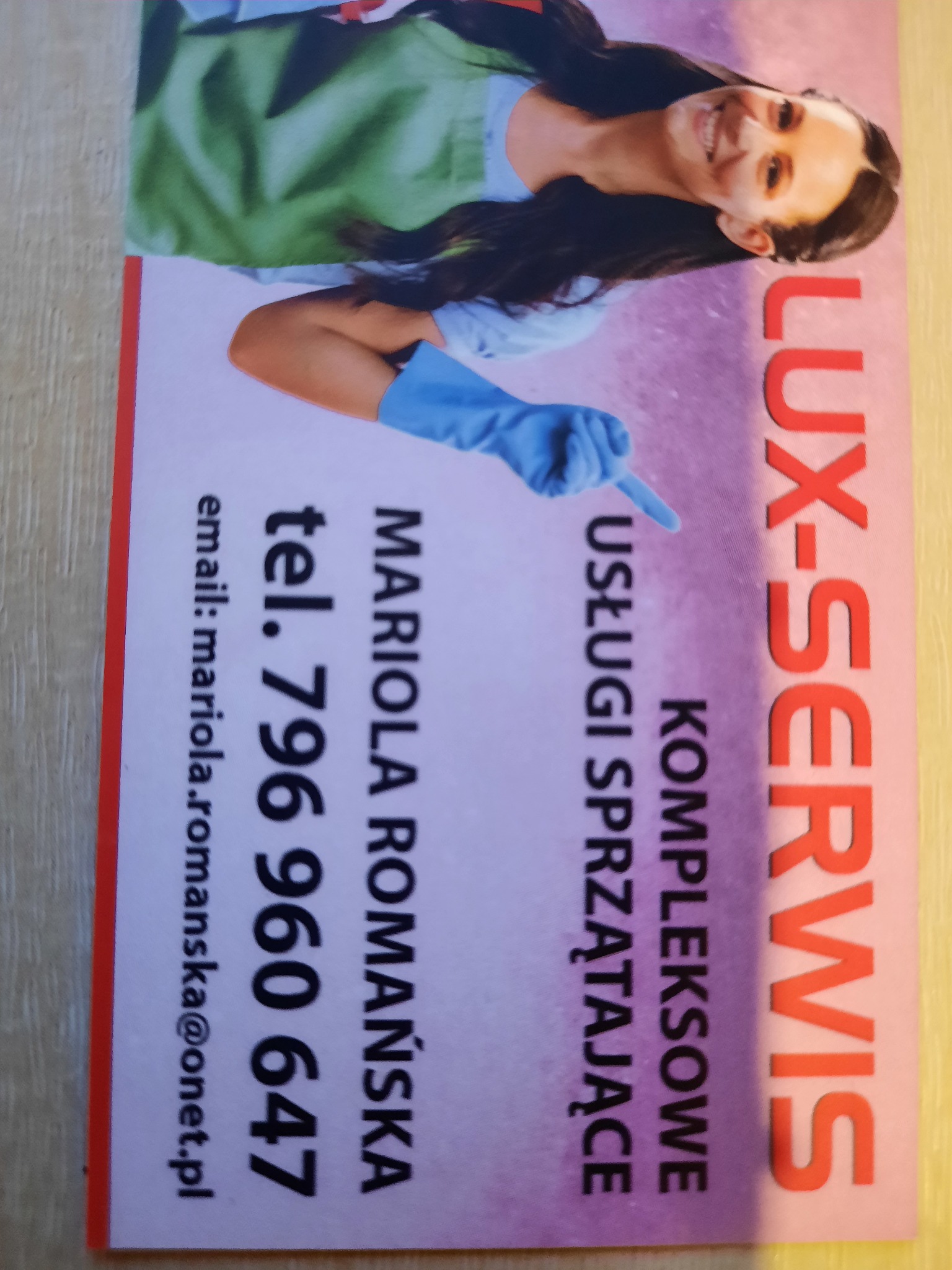 Wizytówka firmy Lux-Servis Mariola Romańska z uśmiechniętą kobietą w rękawicach, oferującej kompleksowe usługi sprzątające, z podanym numerem telefonu i adresem email.