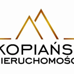 Logo firmy 'Zakopiańskie Nieruchomości' z motywem górskim w kolorze złotym na białym tle.