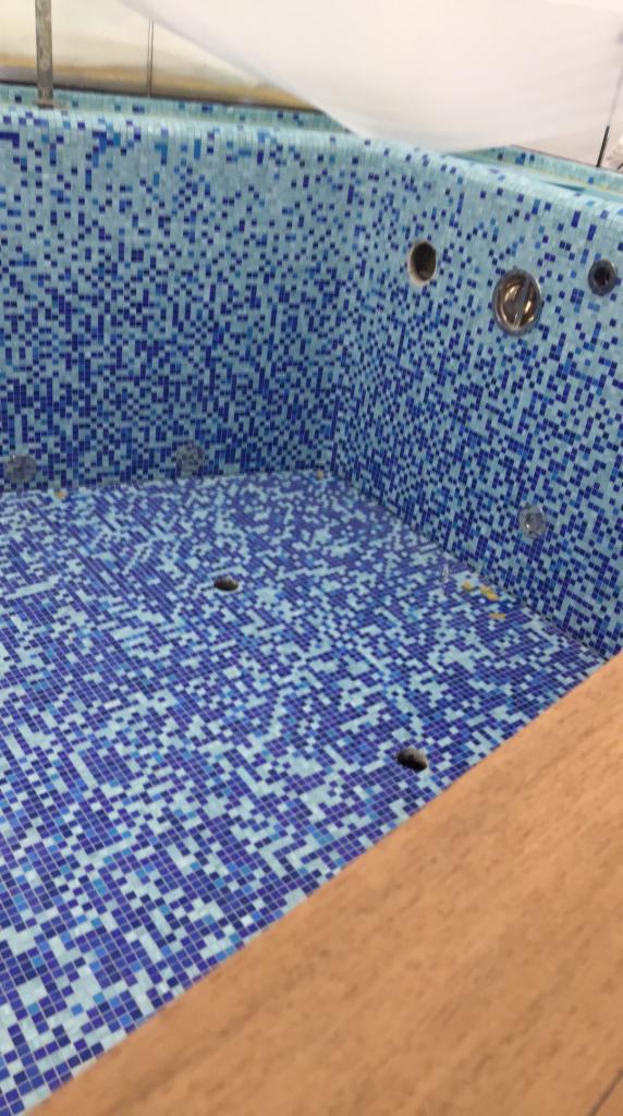 Wyłożona mozaiką w odcieniach błękitu niecka basenowa z przygotowanymi otworami na dysze, widoczna z perspektywy górnej w trakcie prac wykończeniowych we Wrocławiu.