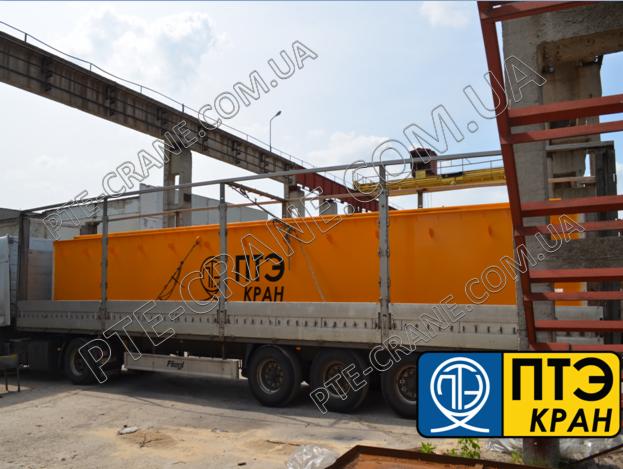 Żółty kontener z logo firmy transportowany na naczepie ciężarówki, widoczny fragment konstrukcji stalowej i betonowy słup w tle.