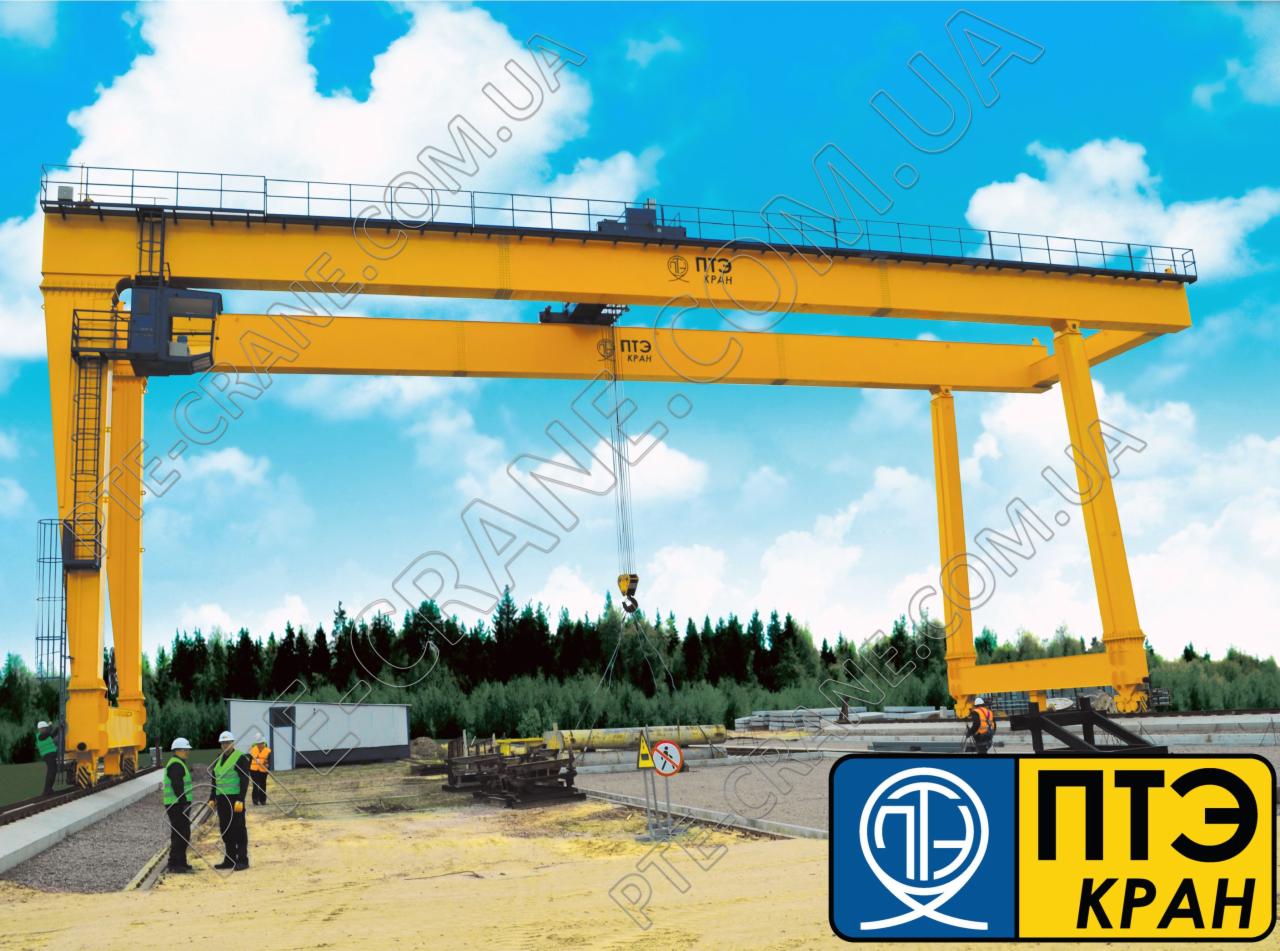 Żółty suwnicowy dźwig bramowy z logo producenta, widoczni pracownicy w odblaskowych kamizelkach przy torach kolejowych.