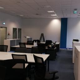 WYKOREM Sp. z o.o. - Przygotowane do użytku, odświeżone biuro w Ćwiklicach z białymi biurkami i czarnymi krzesłami, widoczne ślady malowania ścian i sufitu, pozostawione drabiny malarskie.