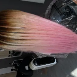 Włosy ombre z brązowych u nasady przechodzące w jasny róż, leżące na folii ochronnej w salonie.