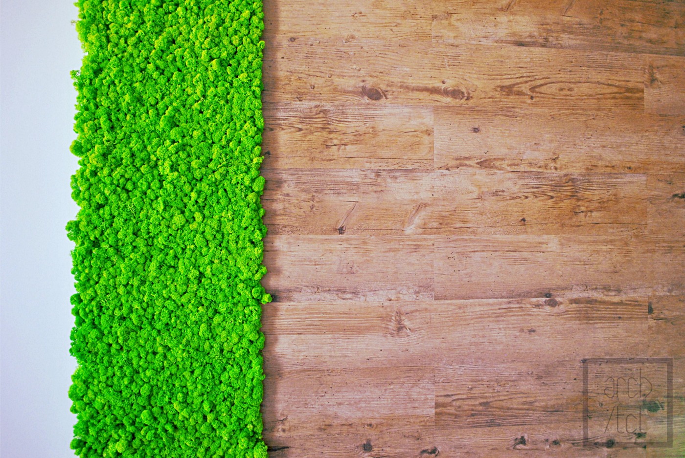 Fragment ściany z drewnianych paneli sąsiadujący z pionowym pasem jasnej, zielonej roślinności, prawdopodobnie mchu, na białym tle. W prawym dolnym rogu widoczne logo firmy.