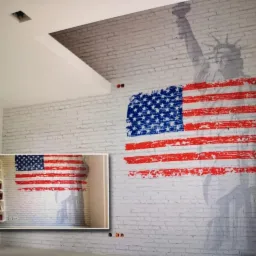 Ściana z białej cegły z motywem flagi USA i sylwetką Statuy Wolności, dodatkowo w lewym dolnym rogu mniejszy obraz tej samej ściany z półkami na ścianie obok.