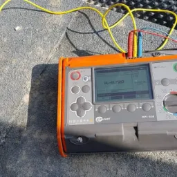 Miernik Sonel MPI-520 z podłączonymi przewodami pomiarowymi, wskazujący wartość rezystancji 0.72Ω, leżący na szarej, teksturowanej powierzchni.
