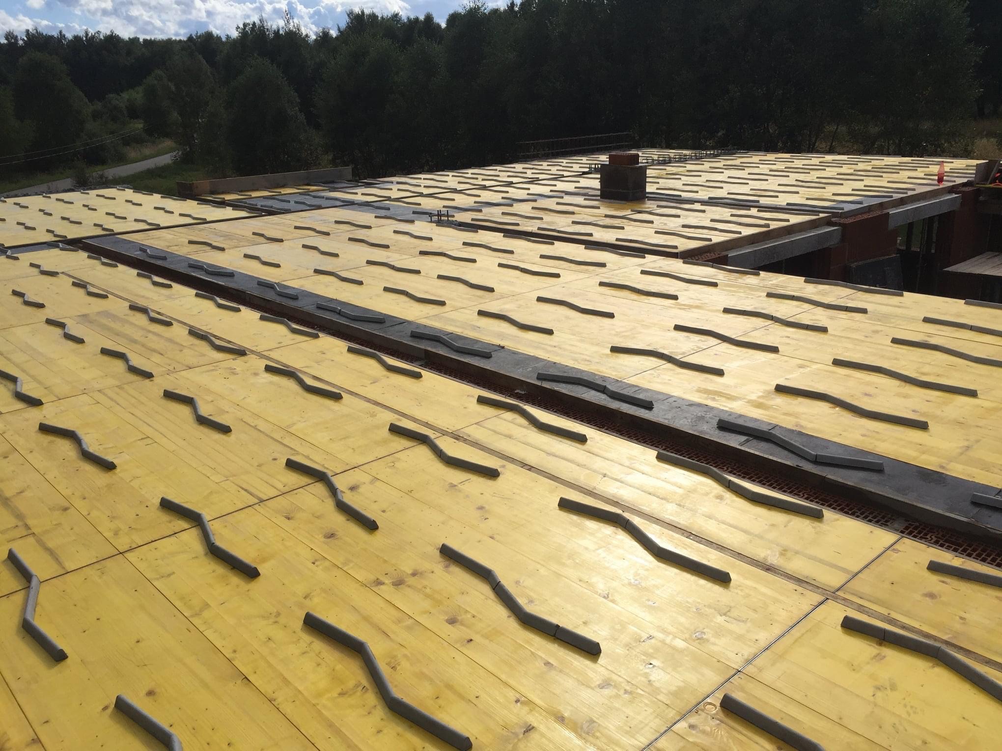 Żółte szalunki stropowe z elementami dystansowymi na budowie domu, widok z góry na konstrukcję w trakcie realizacji.