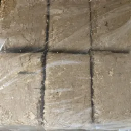 Sześć kostek brykietu drzewnego z widocznymi wiórami, zapakowanych w przezroczystą folię.