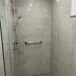 Mama Na Sterydach - Nowoczesna kabina prysznicowa z szarymi płytkami imitującymi marmur, chromowaną armaturą i uchwytem dla niepełnosprawnych. Minimalistyczny design, odpływ liniowy.
