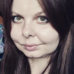 Portret kobiety o brązowych włosach i piwnych oczach, z delikatnym uśmiechem. Naturalne oświetlenie podkreśla rysy twarzy. Ujęcie od przodu, skupione na twarzy.