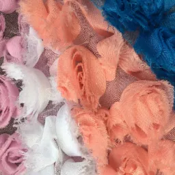 Różnokolorowe, tekstylne różyczki (różowe, białe, brzoskwiniowe i niebieskie) na siatce, makro.