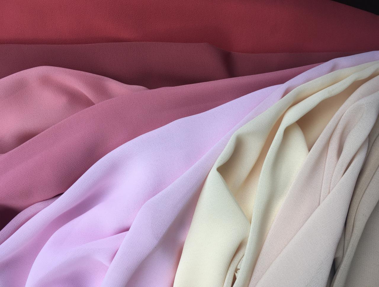 Fałdy delikatnych tkanin w odcieniach różu, beżu i czerwieni, ukazujące subtelną teksturę materiałów.