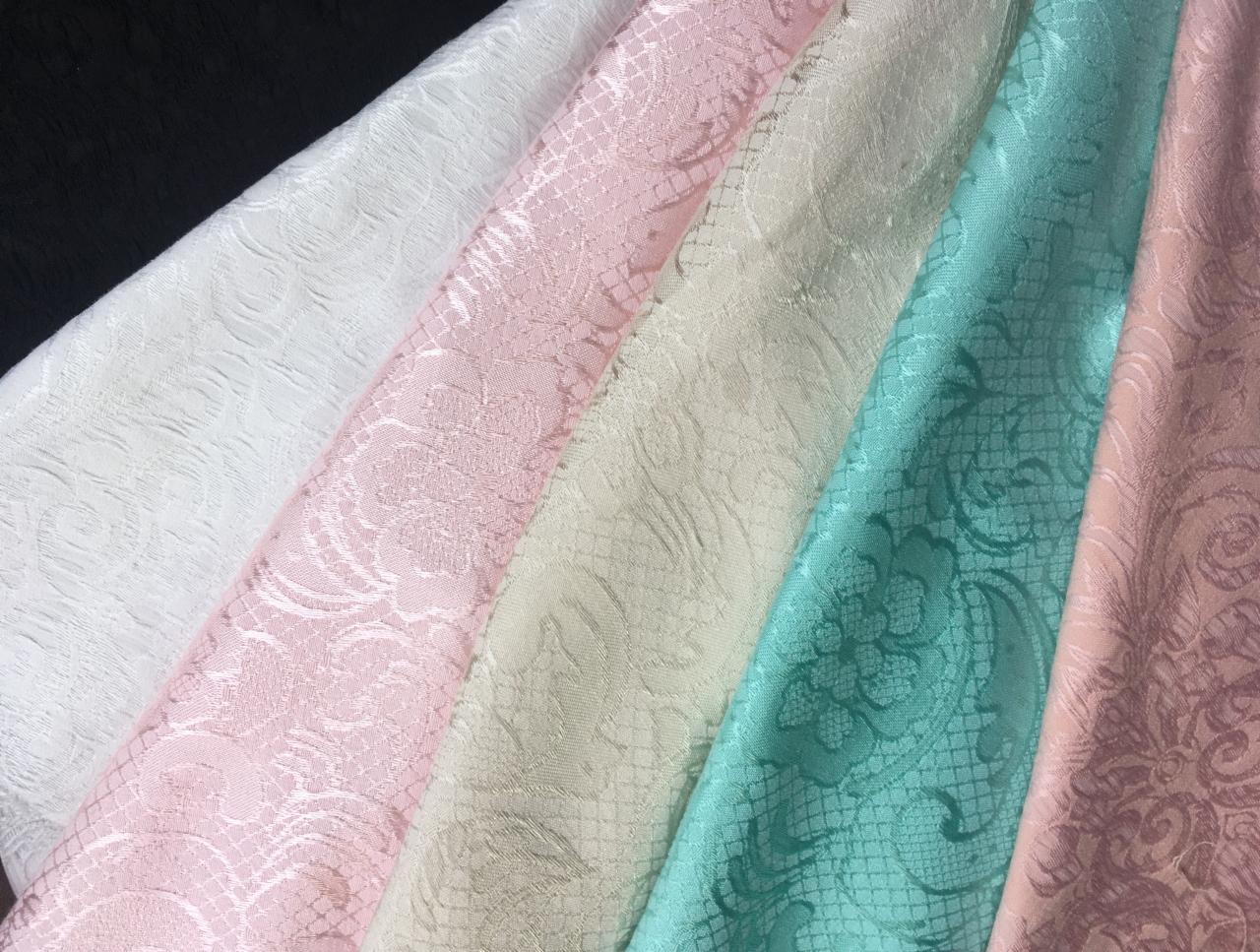 Próbki tkanin dekoracyjnych o różnych wzorach i kolorach (biały, różowy, beżowy, turkusowy, łososiowy) prezentowane w Kielcach.