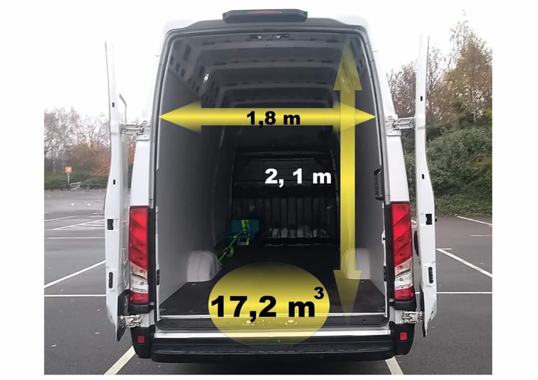 Wnętrze białego busa z otwartymi drzwiami, widoczne wymiary przestrzeni ładunkowej zaznaczone żółtymi strzałkami i wartościami: 1.8m szerokości, 2.1m wysokości i 17.2m3 pojemności.