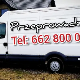 Biały samochód dostawczy z napisem 'Przeprowadzki' i numerem telefonu 662 800 062 na tle domu w budowie.