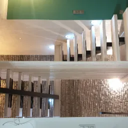 Nowoczesne schody z białymi stopniami i czarnymi wspornikami, widok z góry, ściana wykończona dekoracyjną cegłą, zielona ściana w tle.