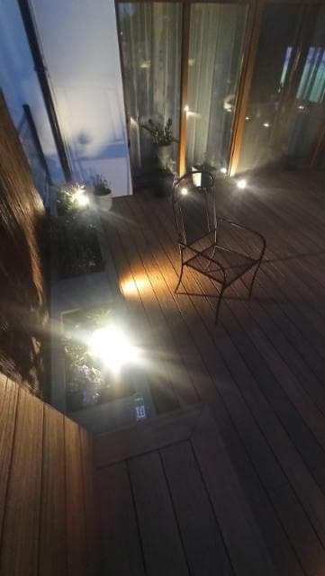 Drewniany taras z krzesłem i oświetleniem punktowym, widok z góry, wieczorny klimat.