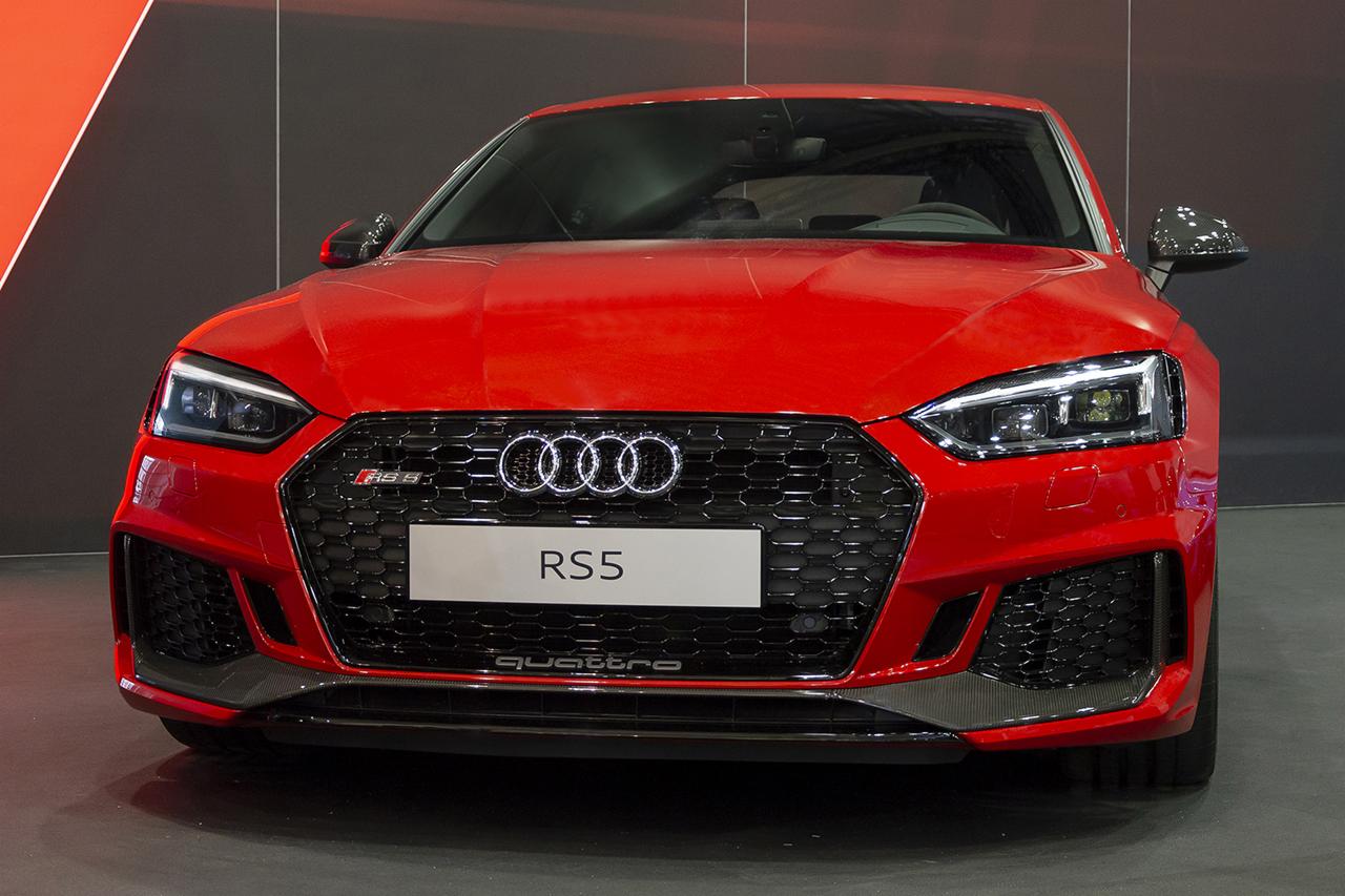 Czerwony samochód Audi RS5 z przodu, z widocznym grillem, logo Audi i reflektorami LED.